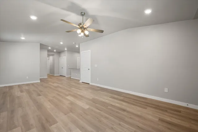 an empty room with wooden floor and fan