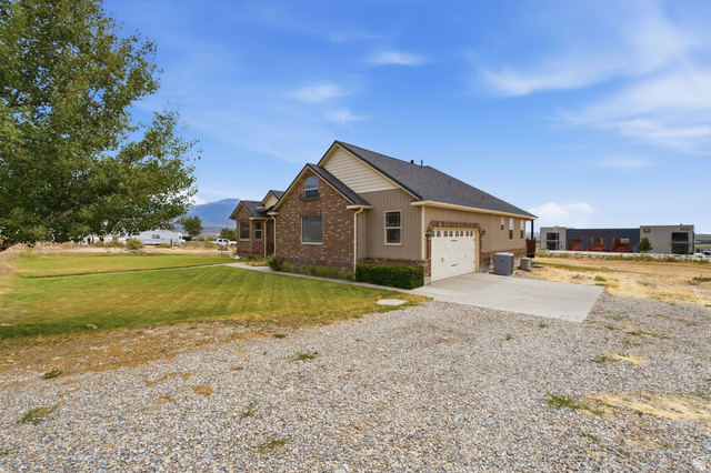 2567 West Rim Rock Drive Stockton, UT 84071 - Photo 4 of 64 Traditional style residence featuring a brick and siding exterior, an attached two-car garage, and a concrete driveway