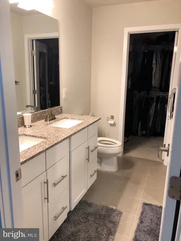 a bathroom with a granite countertop sink toilet and mirror