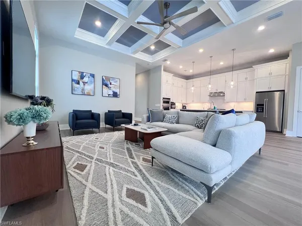 a living room with furniture a chandelier and a dining table with wooden floor