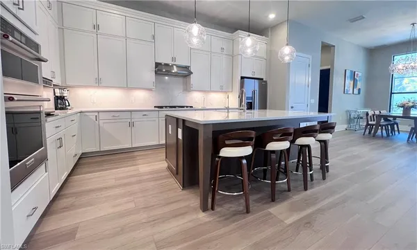 a kitchen with stainless steel appliances granite countertop a table chairs sink and cabinets