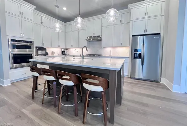 a kitchen with granite countertop a table chairs stove refrigerator and cabinets