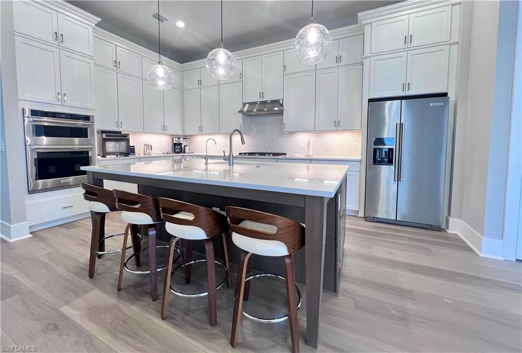 9124 Raintree Street Naples, FL 34114 - Photo 6 of 42 a kitchen with granite countertop a table chairs stove refrigerator and cabinets