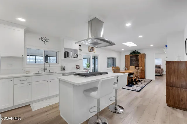 a kitchen with stainless steel appliances a sink a stove a refrigerator cabinets and living room view