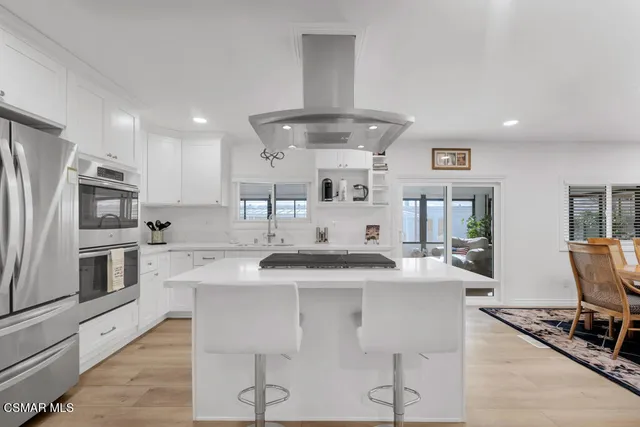a kitchen with stainless steel appliances kitchen island granite countertop a sink and refrigerator