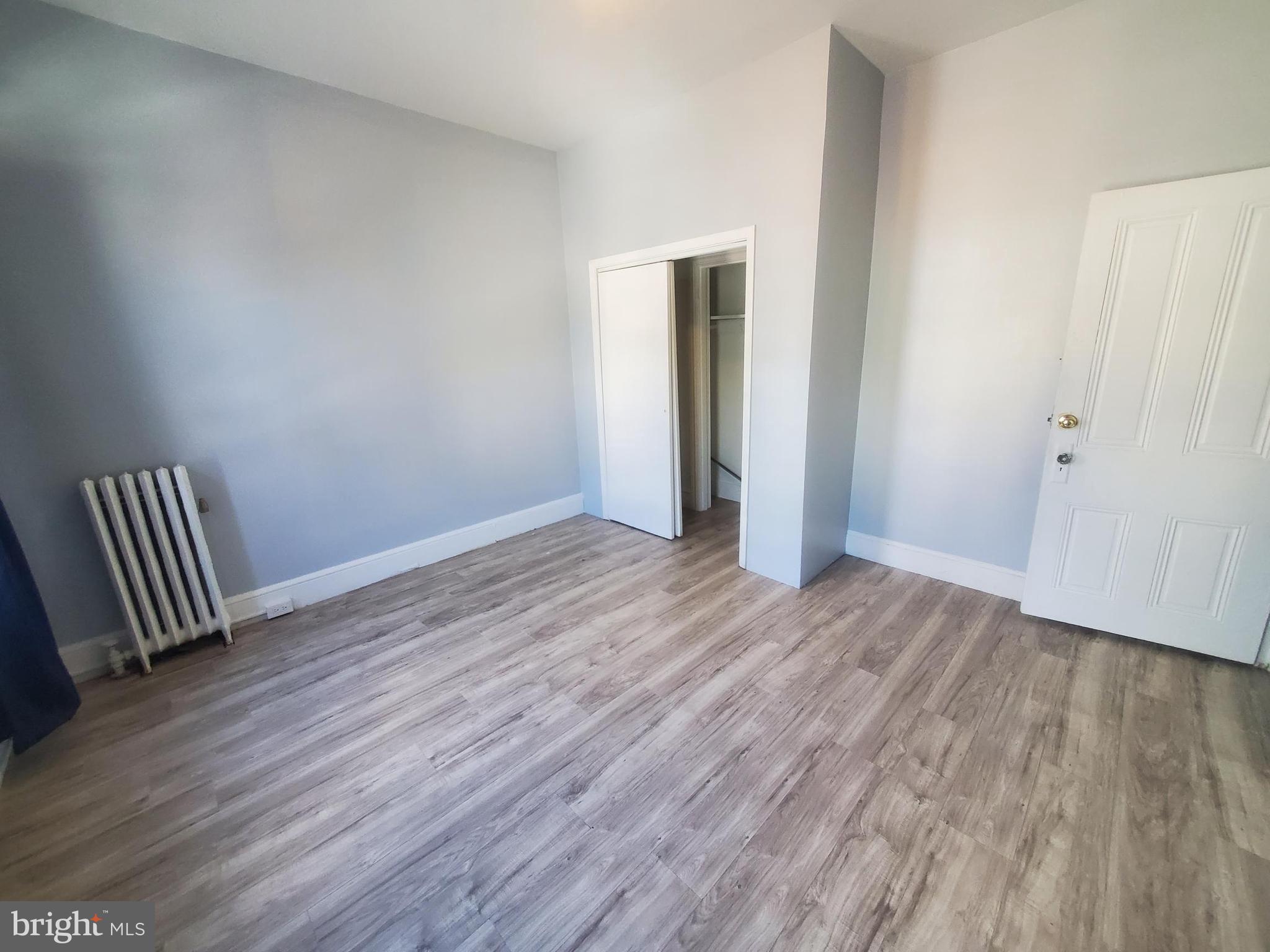 608 North 10th Street, Unit 2 Reading, PA 19604 - Photo 11 of 15 an empty room with wooden floor and a hallway