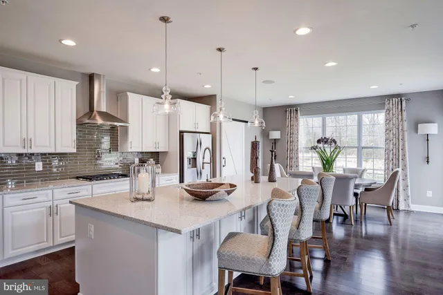 a kitchen with stainless steel appliances kitchen island granite countertop a dining table chairs and white cabinets