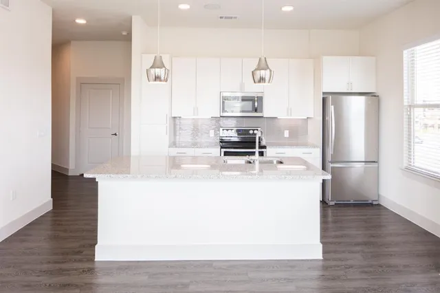 a view of a kitchen with stainless steel appliances a refrigerator and a stove top oven