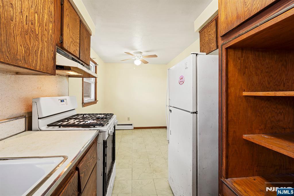 677 Greeley Avenue Fairview, NJ 07022 - Photo 22 of 34 a kitchen with stainless steel appliances a refrigerator a stove and a sink with wooden floor