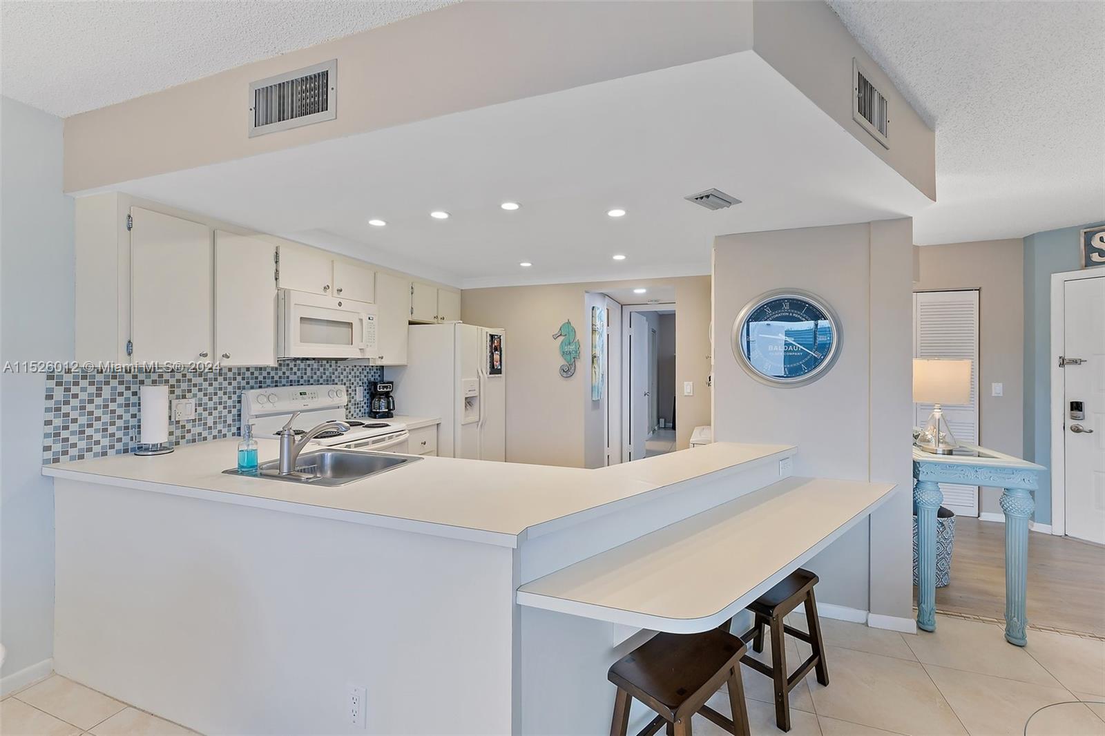 1605 Highway 1, Unit A406 Jupiter, FL 33477 - Photo 12 of 26 a kitchen with stainless steel appliances kitchen island a table and chairs in it