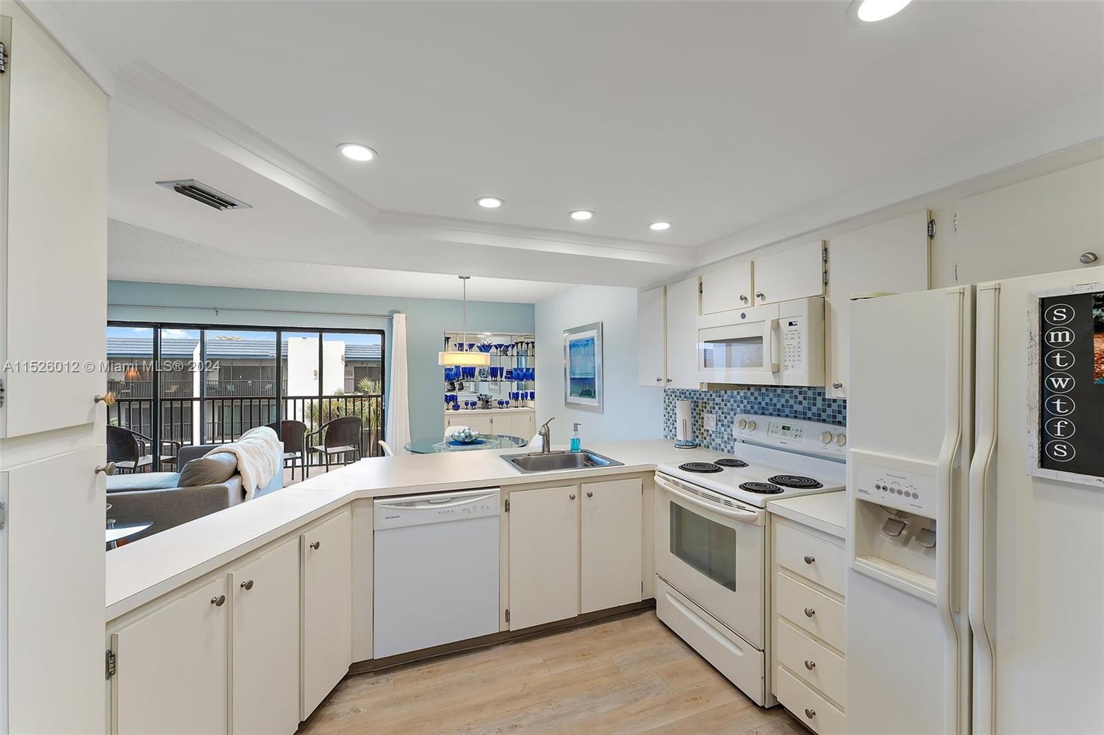 1605 Highway 1, Unit A406 Jupiter, FL 33477 - Photo 14 of 26 a kitchen with white cabinets and white appliances