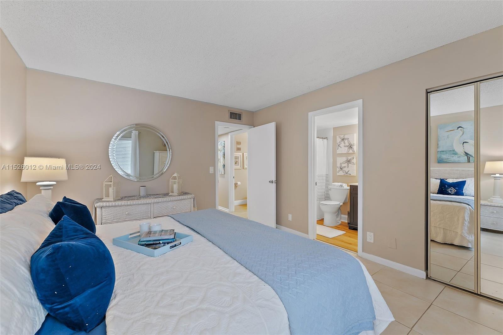 1605 Highway 1, Unit A406 Jupiter, FL 33477 - Photo 17 of 26 a bed room with a bed a mirror and lamp