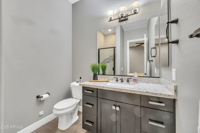 a bathroom with a granite countertop sink a toilet and a mirror