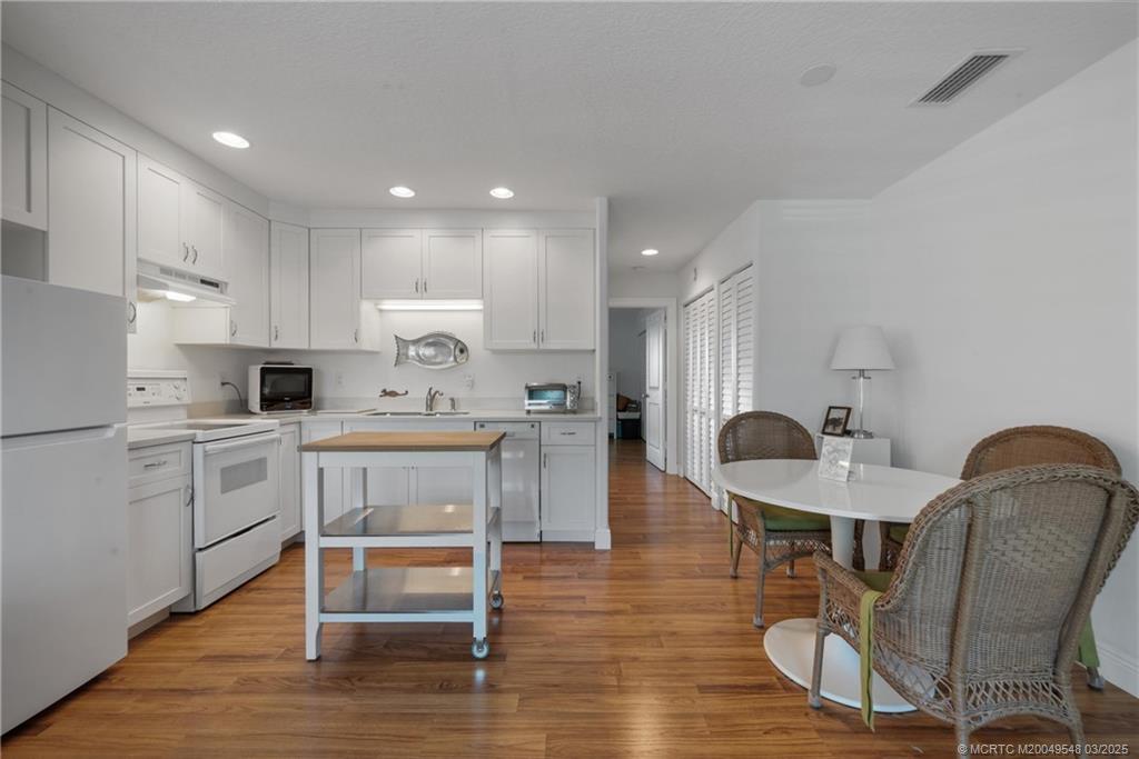 2929 Southeast Ocean Boulevard, Unit K7 Stuart, FL 34996 - Photo 8 of 18 a kitchen with a table chairs refrigerator and microwave