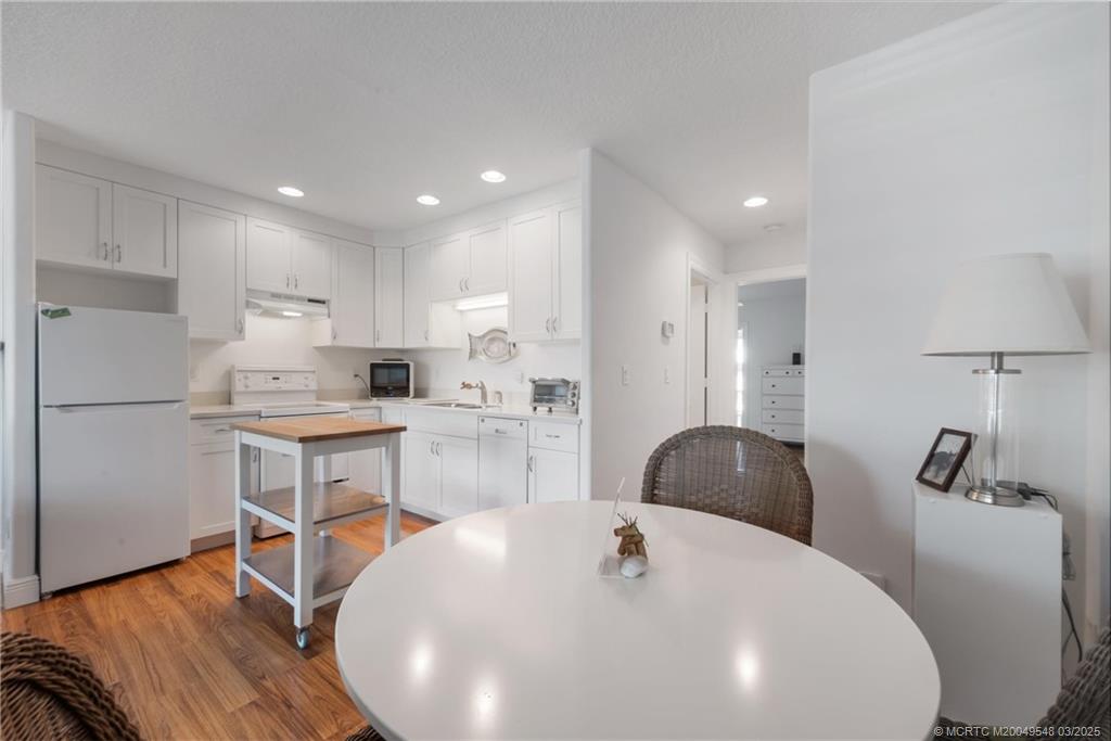2929 Southeast Ocean Boulevard, Unit K7 Stuart, FL 34996 - Photo 9 of 18 a kitchen with stainless steel appliances granite countertop a sink a stove a refrigerator and island with wooden floor