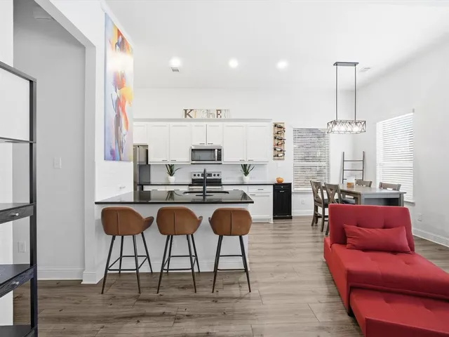 a living room with stainless steel appliances kitchen island granite countertop furniture and a wooden floor