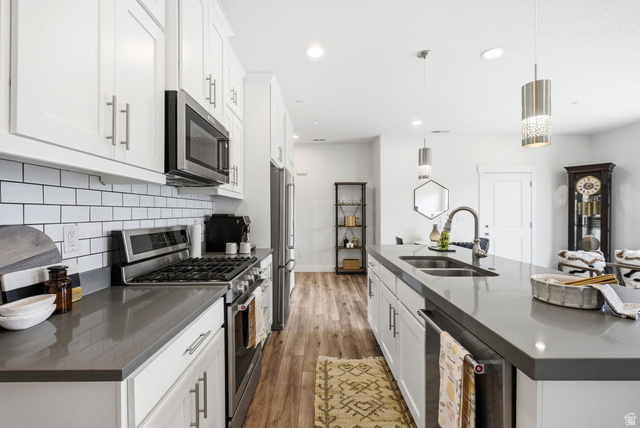 3355 Santa Fe Road Park City, UT 84098 - Photo 7 of 45 Kitchen featuring white shaker cabinetry, stainless steel appliances, grey countertops, white subway tile backsplash, and wood-finish flooring