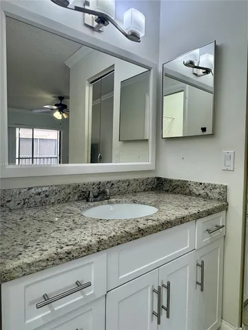 a bathroom with a granite countertop sink and a mirror
