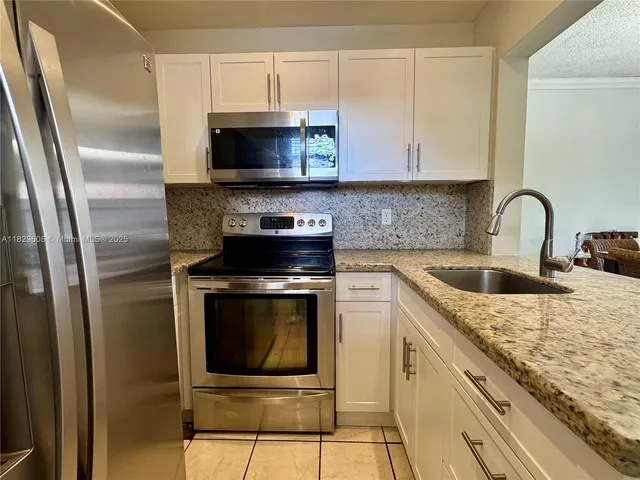 a kitchen with stainless steel appliances granite countertop a stove microwave and sink