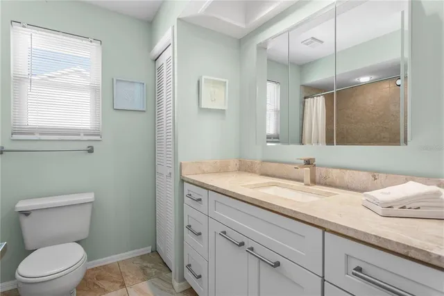 a bathroom with a granite countertop toilet sink and mirror