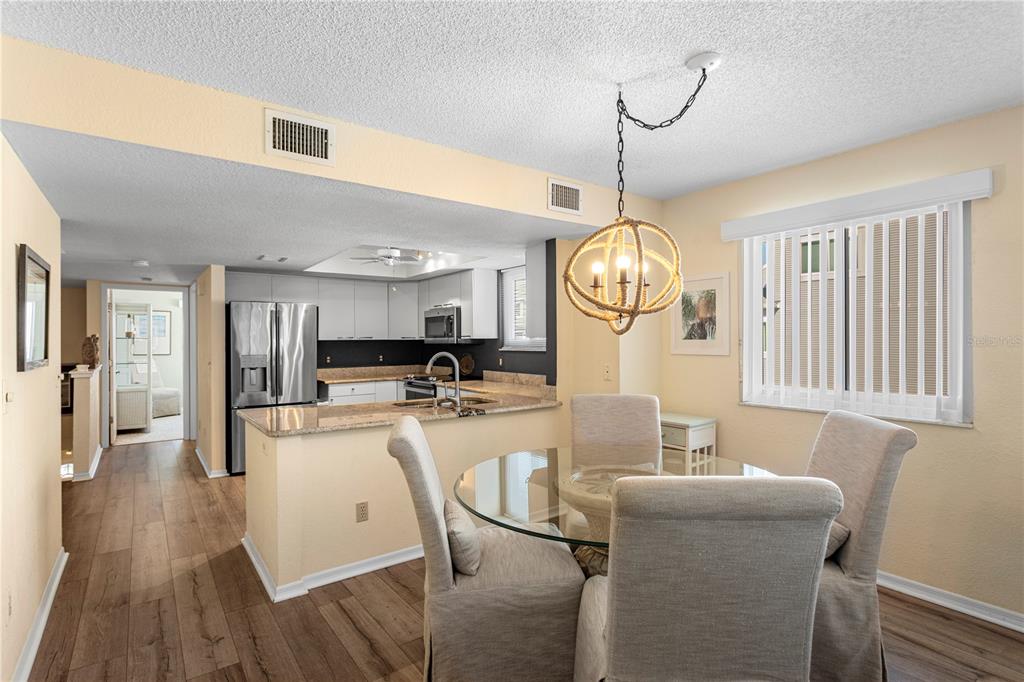 911 Harbour House Drive Indian Rocks Beach, FL 33785 - Photo 10 of 27 a living room with furniture dining table wooden floor and a chandelier