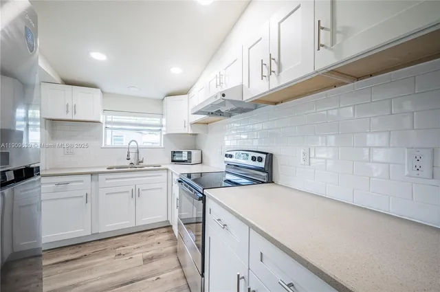 a kitchen with stainless steel appliances granite countertop a sink a stove and cabinets