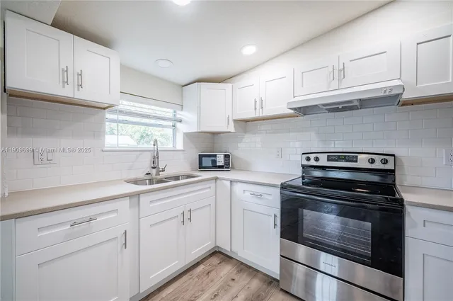 a kitchen with white cabinets and appliances