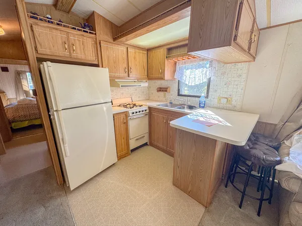 a kitchen with granite countertop a refrigerator a sink a stove and white cabinets