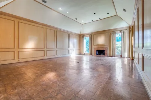 an empty room with wooden floor fireplace and windows