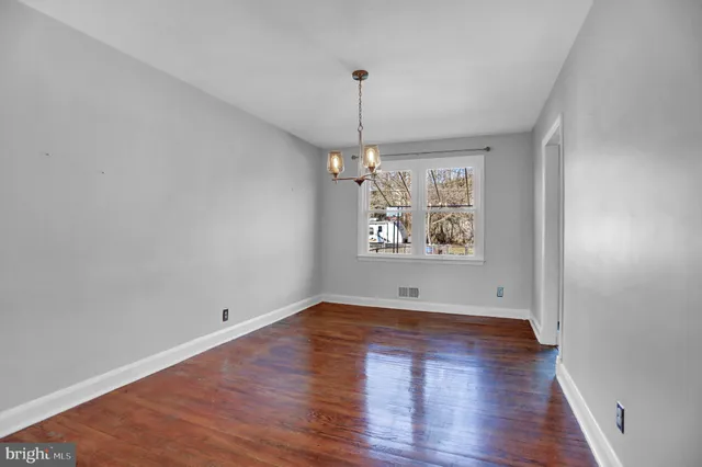 an empty room with wooden floor chandelier and window