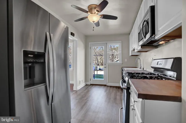 a kitchen with stainless steel appliances granite countertop a refrigerator a stove and a wooden floors