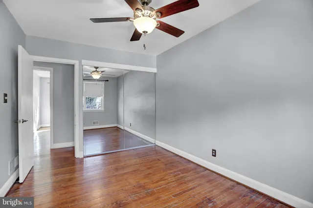 an empty room with wooden floor closet and windows