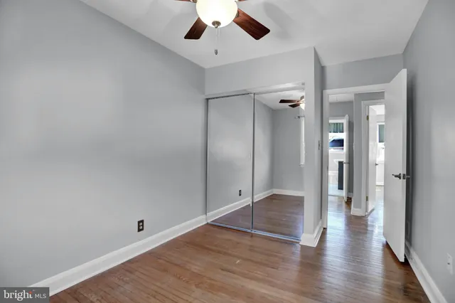 an empty room with wooden floor a ceiling fan and entryway