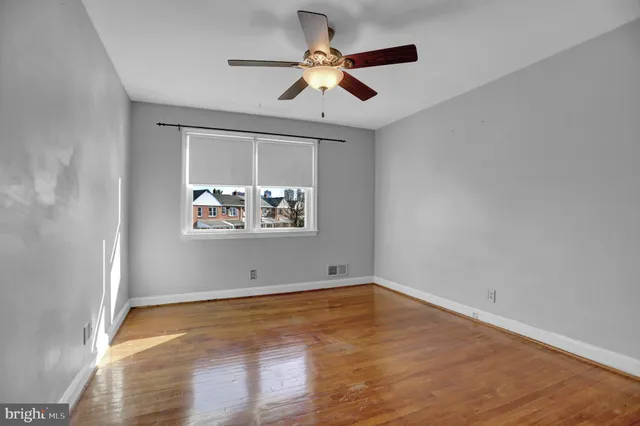 an empty room with wooden floor and ceiling fan