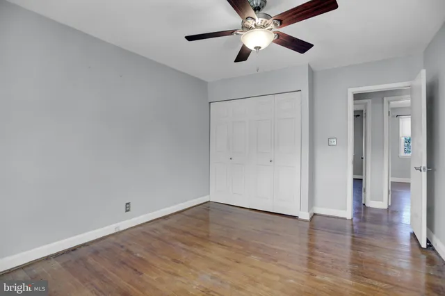 an empty room with wooden floor a ceiling fan and closet