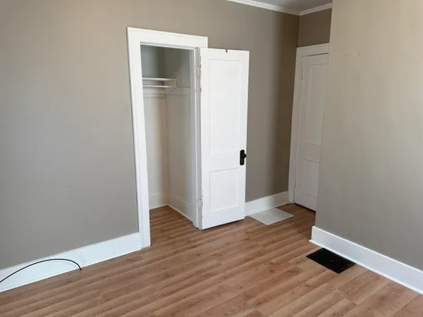a view of an empty room with wooden floor and closet