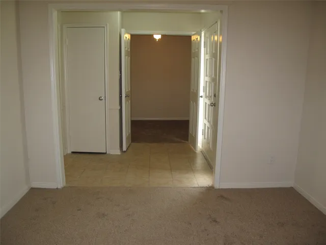 an empty room with a fireplace and chandelier fan