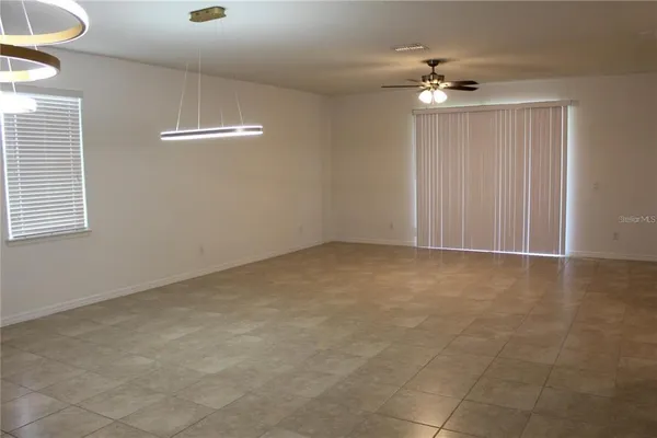 a view of an empty room with a chandelier fan