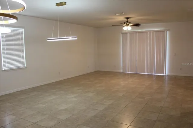 a view of an empty room with a chandelier fan