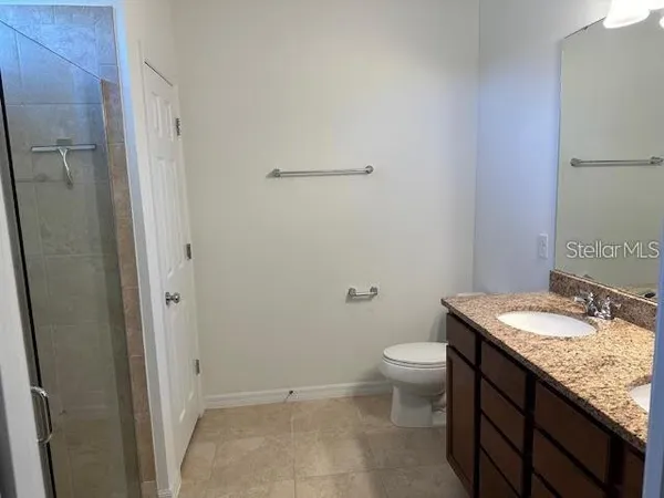 a bathroom with a granite countertop sink a toilet and a mirror