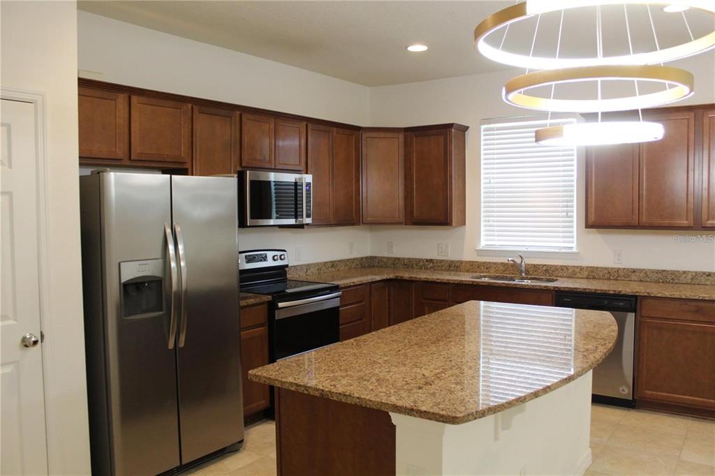 17249 Goldcrest Loop Clermont, FL 34714 - Photo 4 of 29 a kitchen with stainless steel appliances granite countertop a sink stove and refrigerator