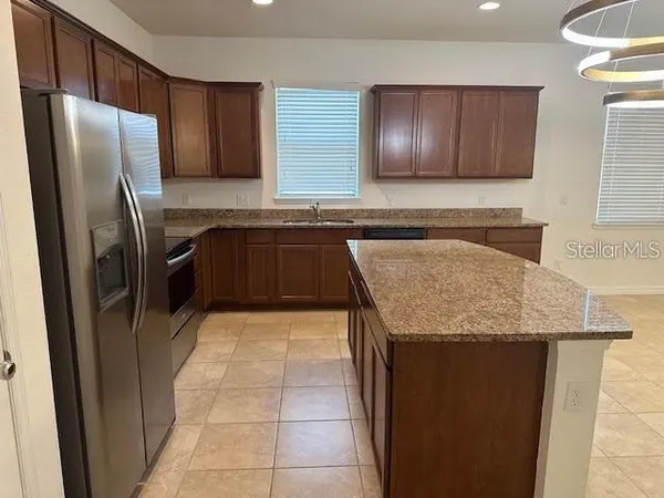 a kitchen with granite countertop stainless steel appliances a refrigerator and a sink