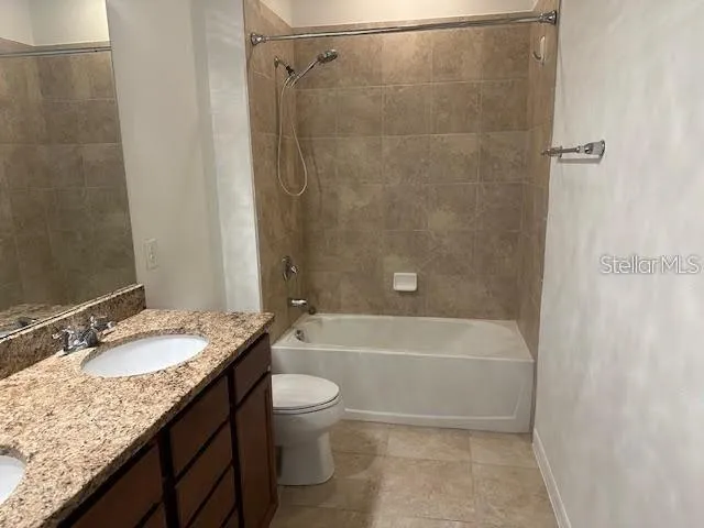 a bathroom with a granite countertop bathtub shower sink vanity and toilet