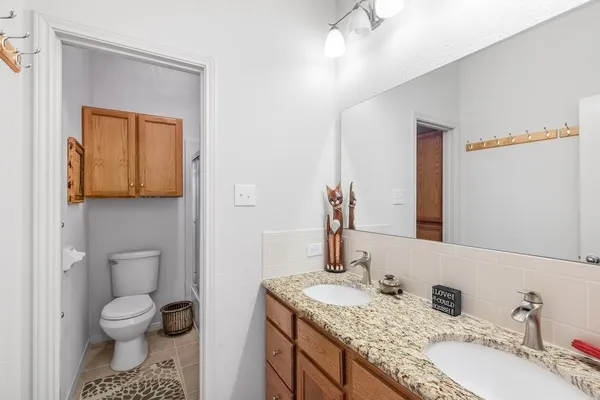 a bathroom with a granite countertop sink toilet and mirror
