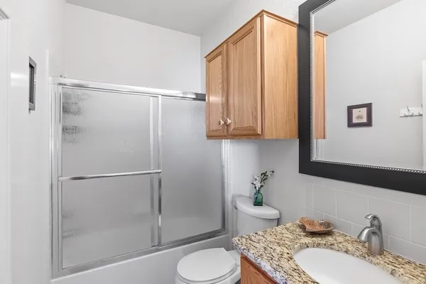 a bathroom with a granite countertop sink toilet and shower