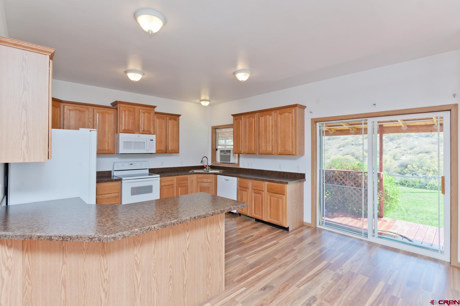 4410 Cedar Road Delta, CO 81416 - Photo 20 of 35 a large kitchen with stainless steel appliances wooden floors and wooden cabinets