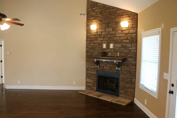 a view of empty room with wooden floor and fireplace