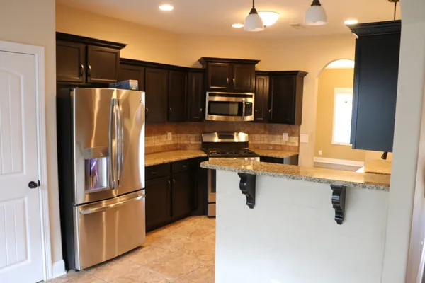 a kitchen with stainless steel appliances granite countertop a refrigerator and a stove top oven