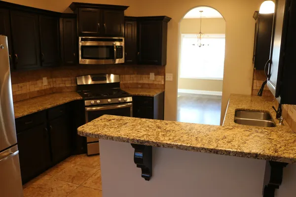 a kitchen with stainless steel appliances granite countertop a sink stove and refrigerator