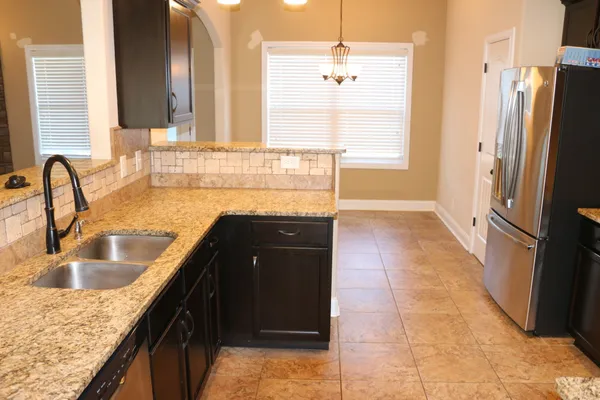 a kitchen with granite countertop a refrigerator and a sink